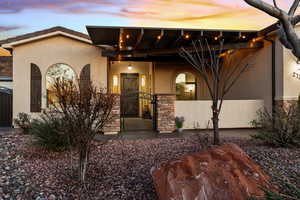 View of front of house with stone siding, a gate, stucco siding, and a porch