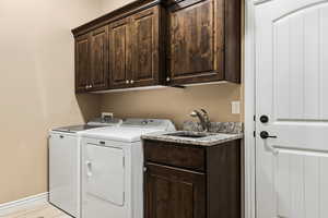 Laundry area with cabinet space, washer and clothes dryer, and light wood finished floors