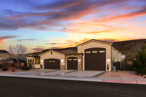 View of front of property featuring an attached garage, stucco siding, a gate, concrete driveway, and stone siding