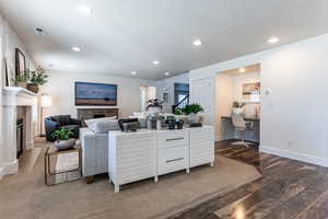 Living area with a high end fireplace, dark wood-type flooring, recessed lighting, and built in desk