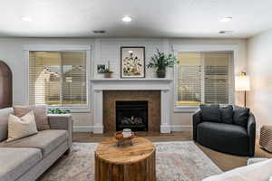 Living room featuring carpet floors, a tile fireplace, a textured ceiling, and recessed lighting