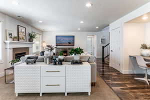 Living area featuring a fireplace, dark wood-style flooring, recessed lighting, a textured ceiling, and dark carpet