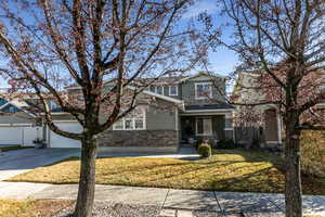 View of front of house featuring stone siding, stucco siding, a front yard, driveway, and a garage