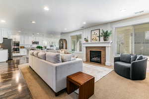 Living room with recessed lighting, a tiled fireplace, a textured ceiling, and dark wood finished floors
