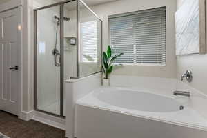 Bathroom featuring a stall shower, a garden tub, and dark tile patterned floors