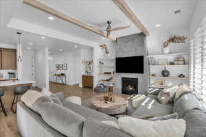 Living area with a ceiling fan, recessed lighting, a fireplace, light wood-style flooring, and beamed ceiling