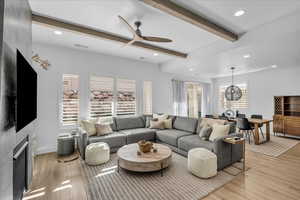 Living room with beamed ceiling, a ceiling fan, recessed lighting, light wood-style flooring, and a fireplace