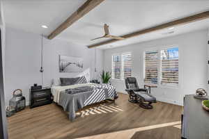 Bedroom with light wood-style floors, ceiling fan, and beamed ceiling