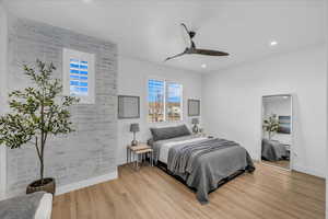 Bedroom featuring light wood-style flooring, a ceiling fan, recessed lighting, and brick wall