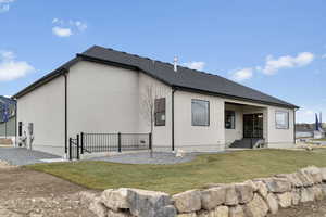 Back of house featuring stucco siding, a yard, and roof with shingles