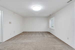 Basement living area featuring light colored carpet