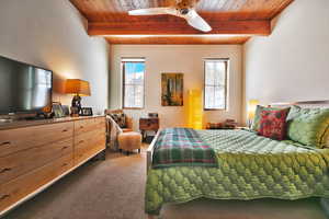 Bedroom featuring a wood ceiling with exposed beams, dark colored carpet, and ceiling fan