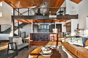 Living room featuring wood ceiling, high vaulted ceiling, wood finished floors, and stairway