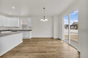 Kitchen with white cabinetry, hanging light fixtures, a chandelier, light wood-style flooring, and recessed lighting