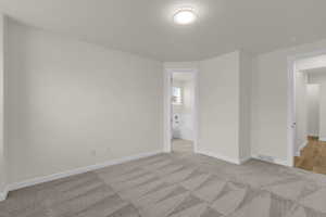 Unfurnished bedroom featuring light colored carpet and connected bathroom