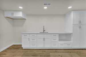 Bar area with white cabinets, light wood-style floors, and recessed lighting