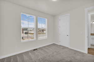 Unfurnished bedroom with light carpet and baseboards