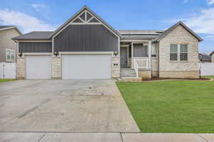View of front of house featuring stone siding, a gate, board and batten siding, and solar panels