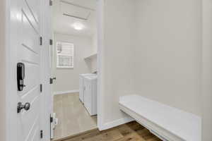 Washroom featuring separate washer and dryer, attic access, and light wood-style flooring