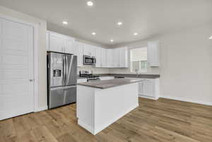 Kitchen with stainless steel appliances, white cabinets, light wood finished floors, and recessed lighting