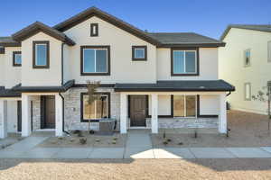 View of front of house featuring stone siding, stucco siding, and a shingle roof