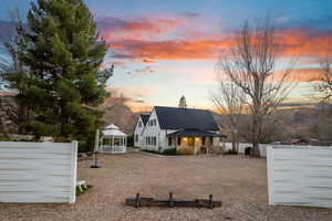 Back of property at dusk featuring a gazebo, a metal roof, a patio area, and a standing seam roof