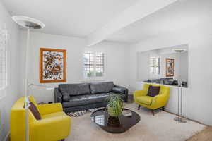 Living area featuring carpet flooring and beam ceiling