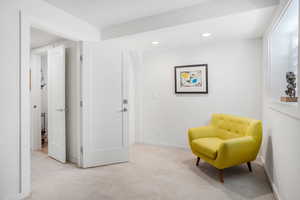 Sitting room with light colored carpet and recessed lighting