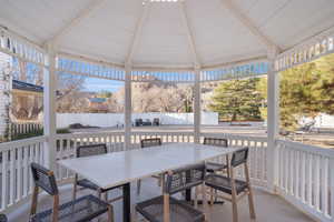 Sunroom featuring outdoor dining space, a patio, beamed ceiling, and a gazebo