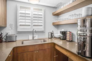 Kitchen with open shelves, light stone counters, and brown cabinetry