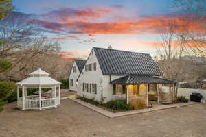 Back of house at dusk featuring a gazebo, a metal roof, a standing seam roof, and a patio