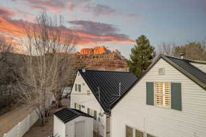 Back of property at dusk featuring a metal roof and a shed