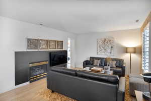 Living area featuring a glass covered fireplace, wood finished floors, and stacked washer / drying machine