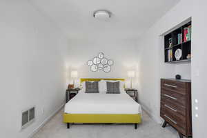 Bedroom with light colored carpet and heating unit