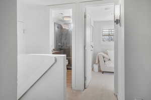 Hall with light colored carpet and baseboards