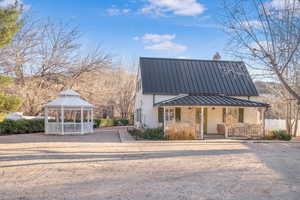 View of front of property featuring a metal roof, a standing seam roof, a gazebo, and covered porch