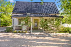 View of front of house featuring a standing seam roof and a porch