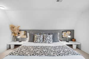Bedroom with light carpet and lofted ceiling