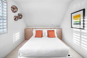 Unfurnished bedroom featuring multiple windows, light carpet, and lofted ceiling
