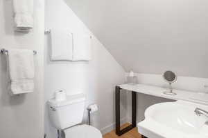 Half bathroom with lofted ceiling and light wood finished floors