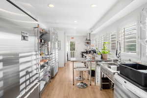 Kitchen featuring high end refrigerator, open shelves, white dishwasher, recessed lighting, and stainless steel counters