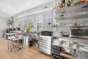 Kitchen featuring open shelves, stainless steel appliances, light wood-style floors, recessed lighting, and wall chimney range hood