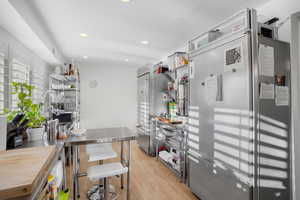 Kitchen featuring stainless steel refrigerator, light wood finished floors, open shelves, stainless steel counters, and freestanding refrigerator