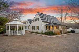 Back of property at dusk featuring a metal roof, a gazebo, a standing seam roof, and a patio