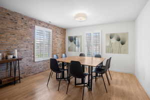 Dining space with brick wall and light wood-type flooring