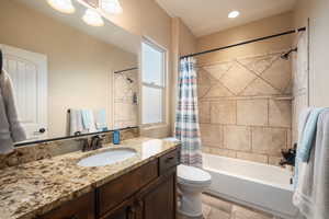 Full bathroom featuring vanity, shower / bath combo, and stone tile floors