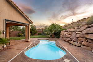 Pool at dusk with a patio area, a fenced backyard, and a pool with connected hot tub