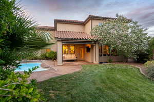 Rear view of house featuring a yard, stucco siding, a patio, an outdoor pool, and a tiled roof