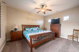Carpeted bedroom with baseboards and a ceiling fan