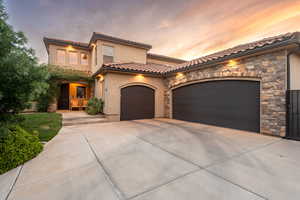 Mediterranean / spanish-style house featuring stone siding, a garage, concrete driveway, stucco siding, and a tile roof